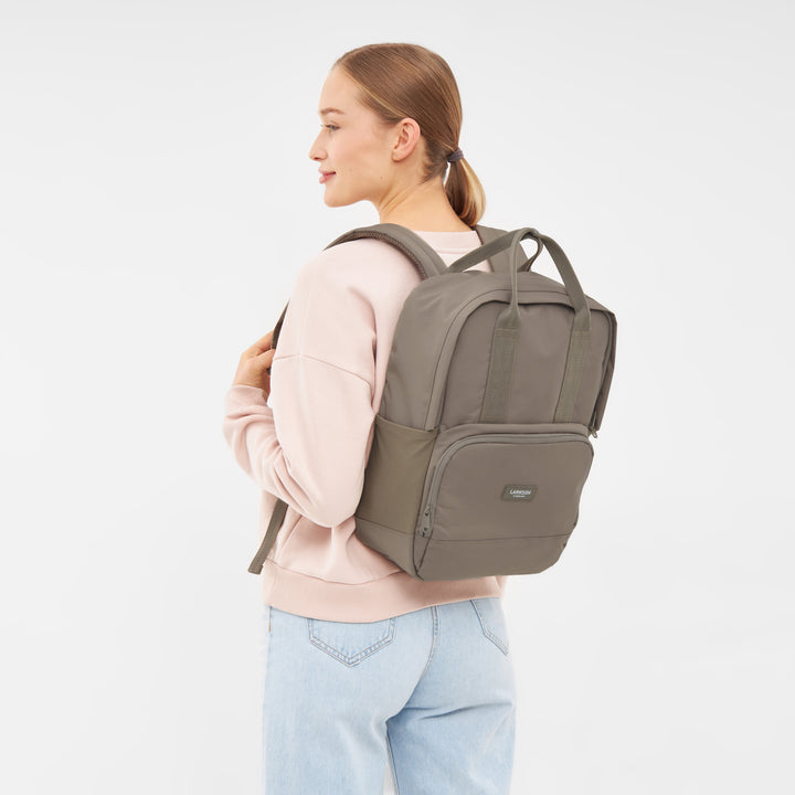 Frau trägt LARKSON Rucksack No 6 in graubraun, moderner, rechteckiger Rucksack mit Fronttasche