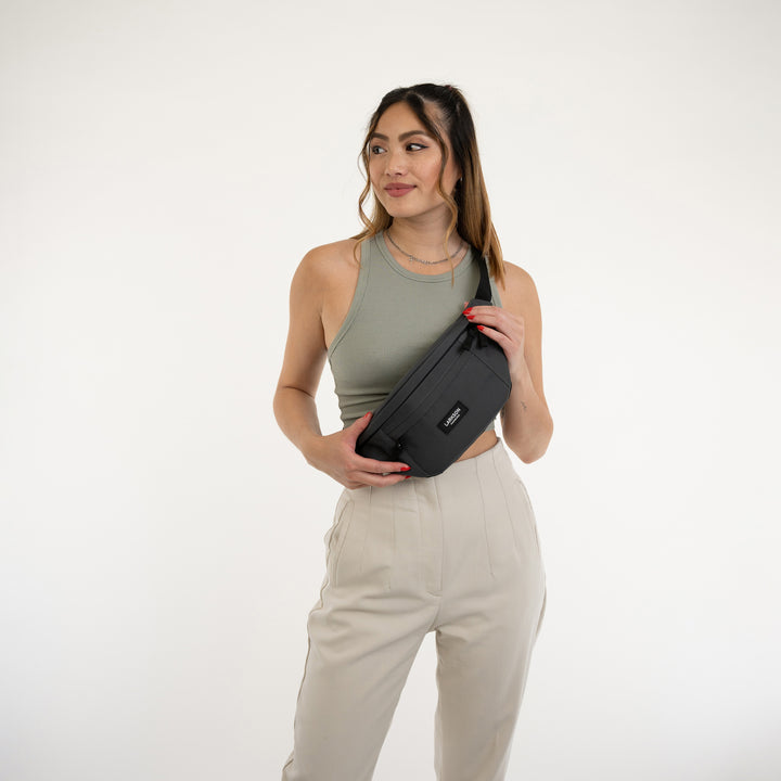 Frau trägt graue LARKSON Bauchtasche Ole quer am Körper über grünes Top und helle Hose