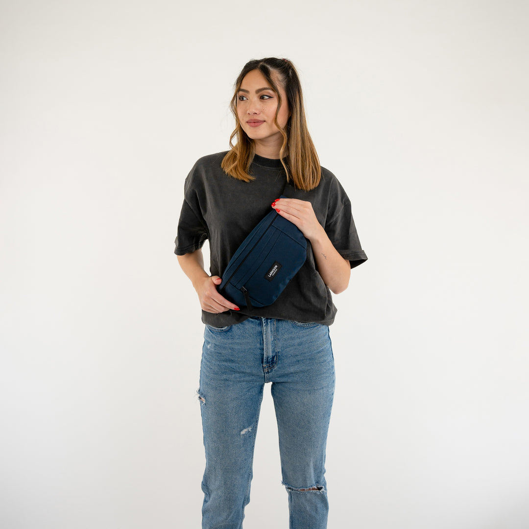 Frau mit dunklem Oberteil und blauer LARKSON Bauchtasche Ole vor weißem Hintergrund