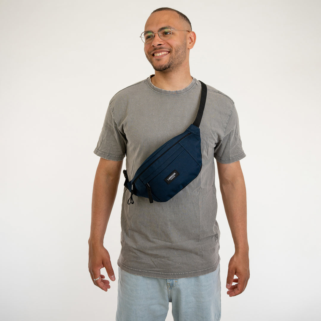 Mann trägt dunkelblaue LARKSON Bauchtasche Ole über grauem T-Shirt