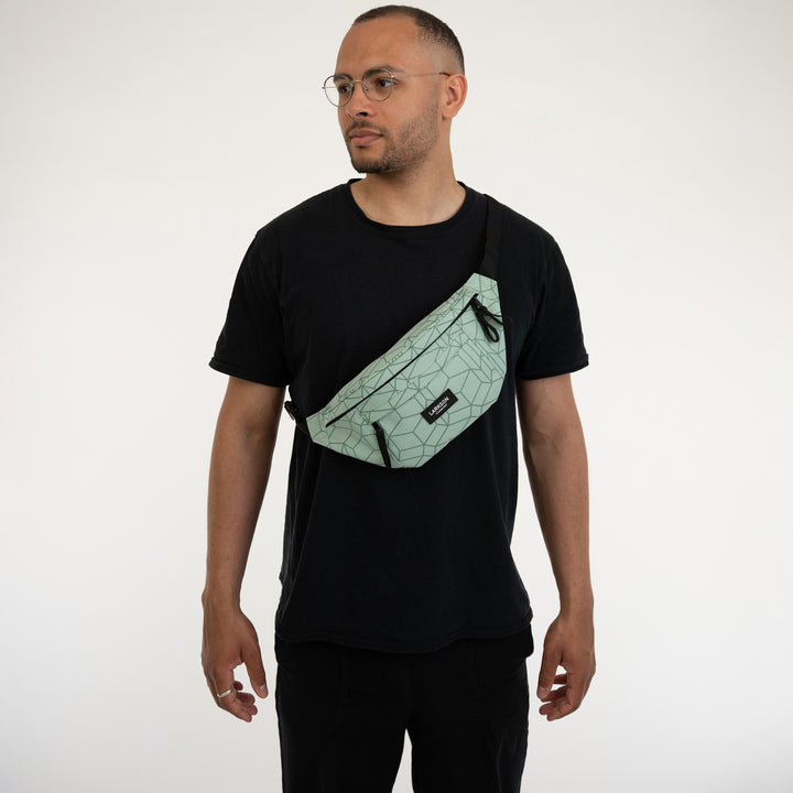 Mann trägt mintfarbene Bauchtasche Ole von Larkson mit geometrischem Muster quer über dem schwarzen T-Shirt