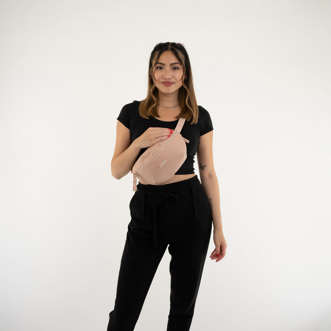 Frau trägt rosa Bauchtasche Finn von Larkson über schwarzem Oberteil und Hose