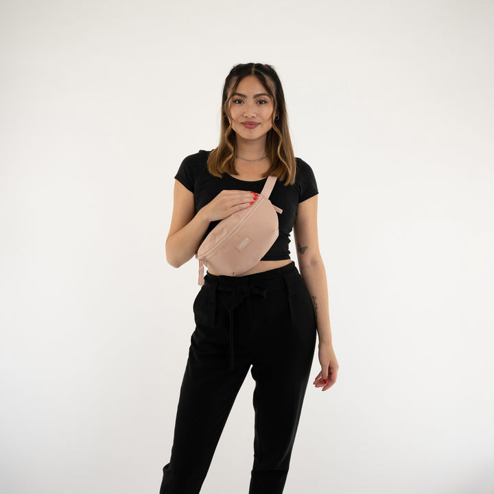 Frau trägt rosa Bauchtasche Finn von Larkson über schwarzem Oberteil und Hose