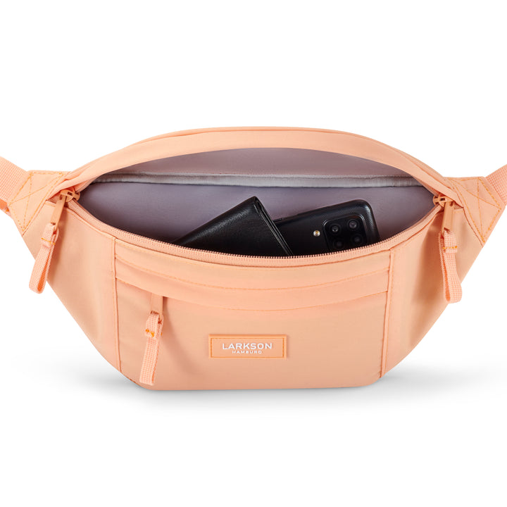 Pfirsichfarbene Bauchtasche Ole von Larkson mit geöffnetem Hauptfach und sichtbarem Geldbeutel und Smartphone