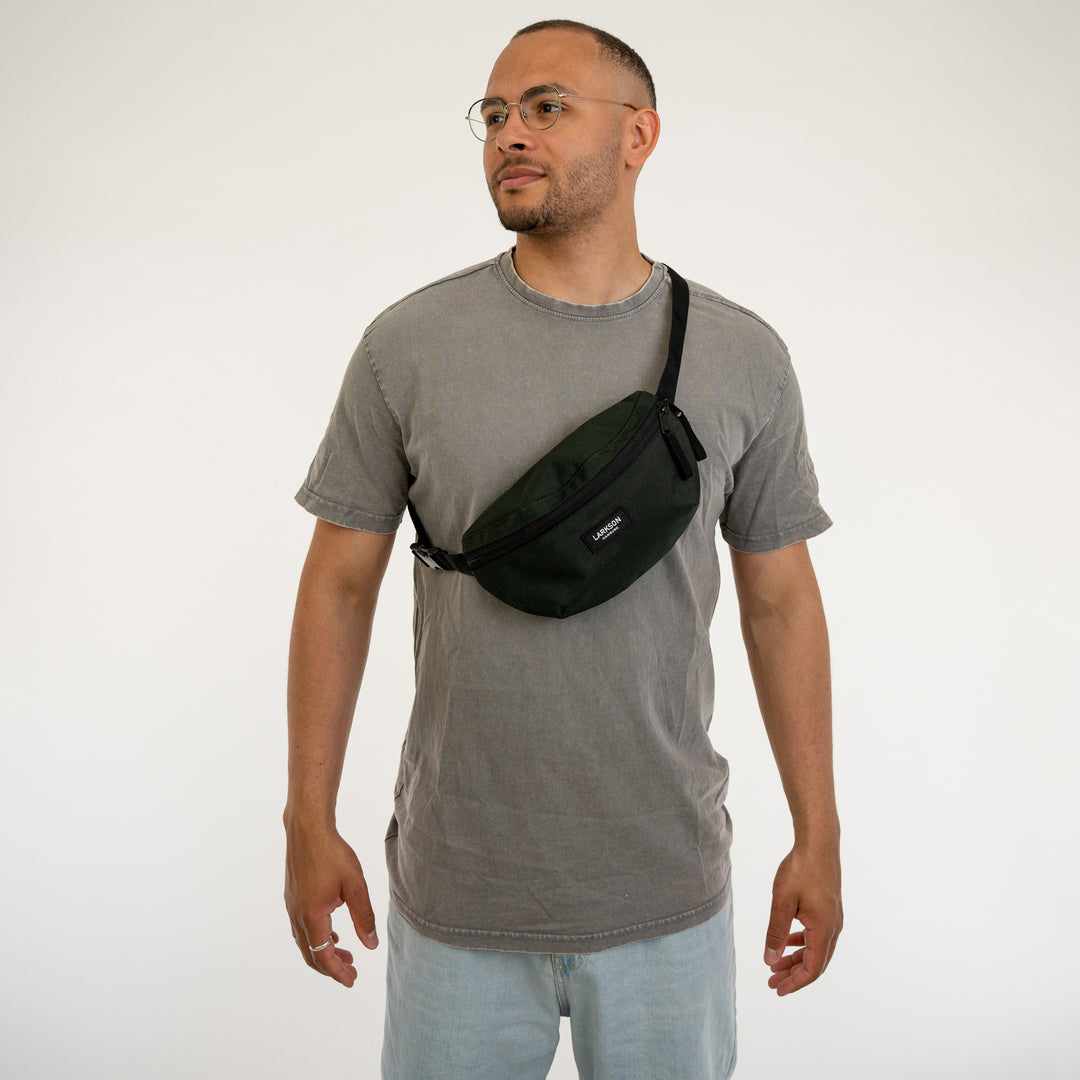 Mann trägt grüne Bauchtasche Finn von Larkson über grauem T-Shirt und hellen Jeans
