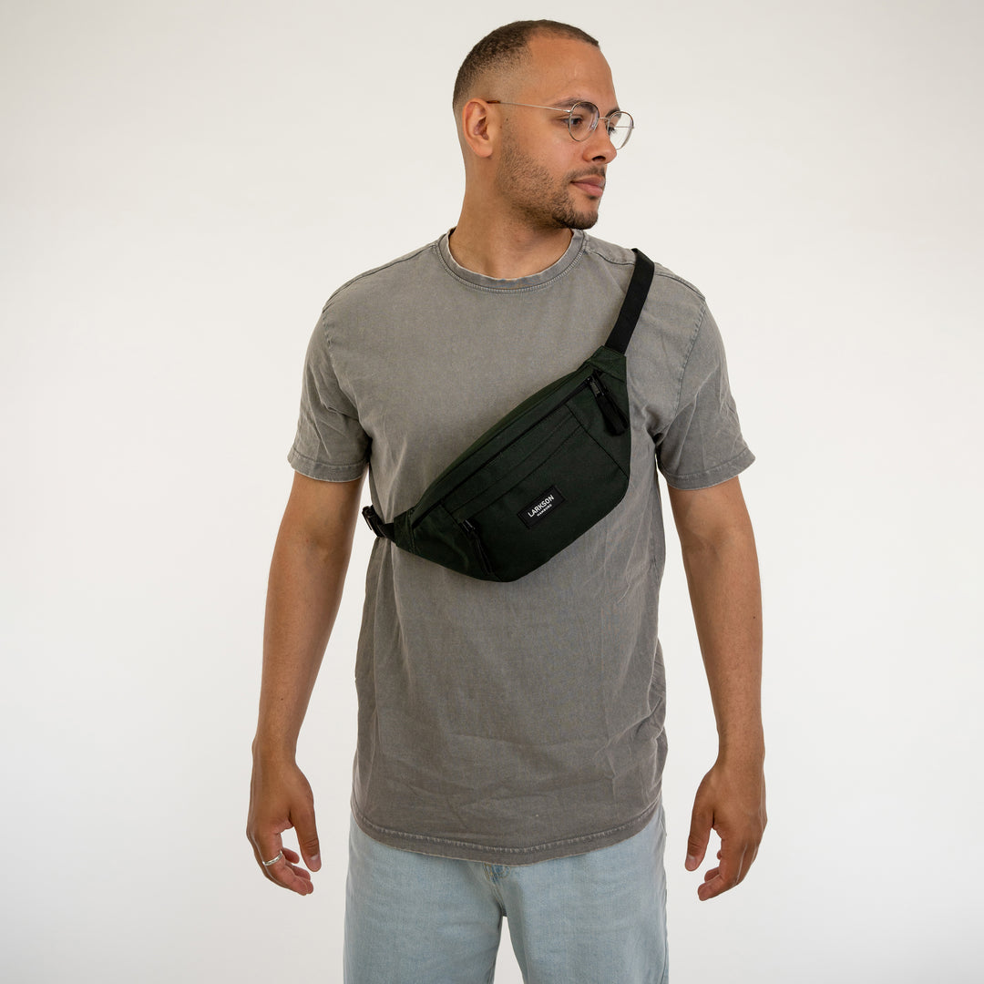 Mann trägt grüne Bauchtasche Ole von Larkson quer über Brust mit grauem T-Shirt und hellem Jeans