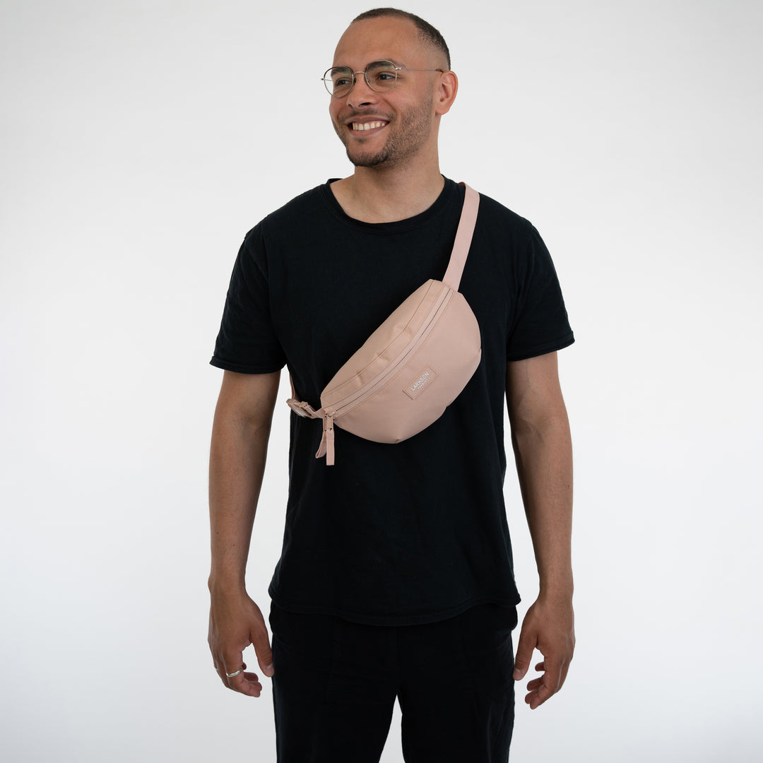 Mann trägt rosa Bauchtasche Finn von Larkson über der Schulter mit schwarzem T-Shirt