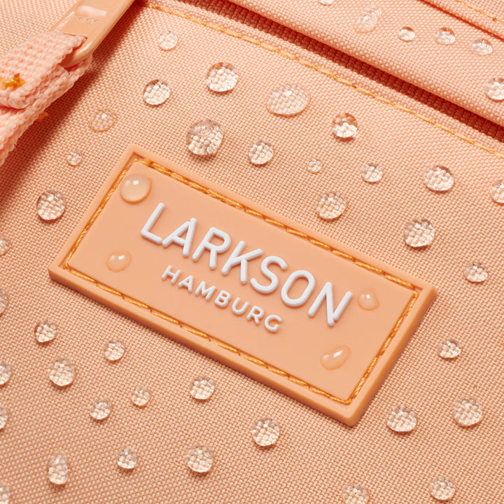 Nahaufnahme eines wasserabweisenden peachfarbenen LARKSON Bauchtasche mit Wassertropfen