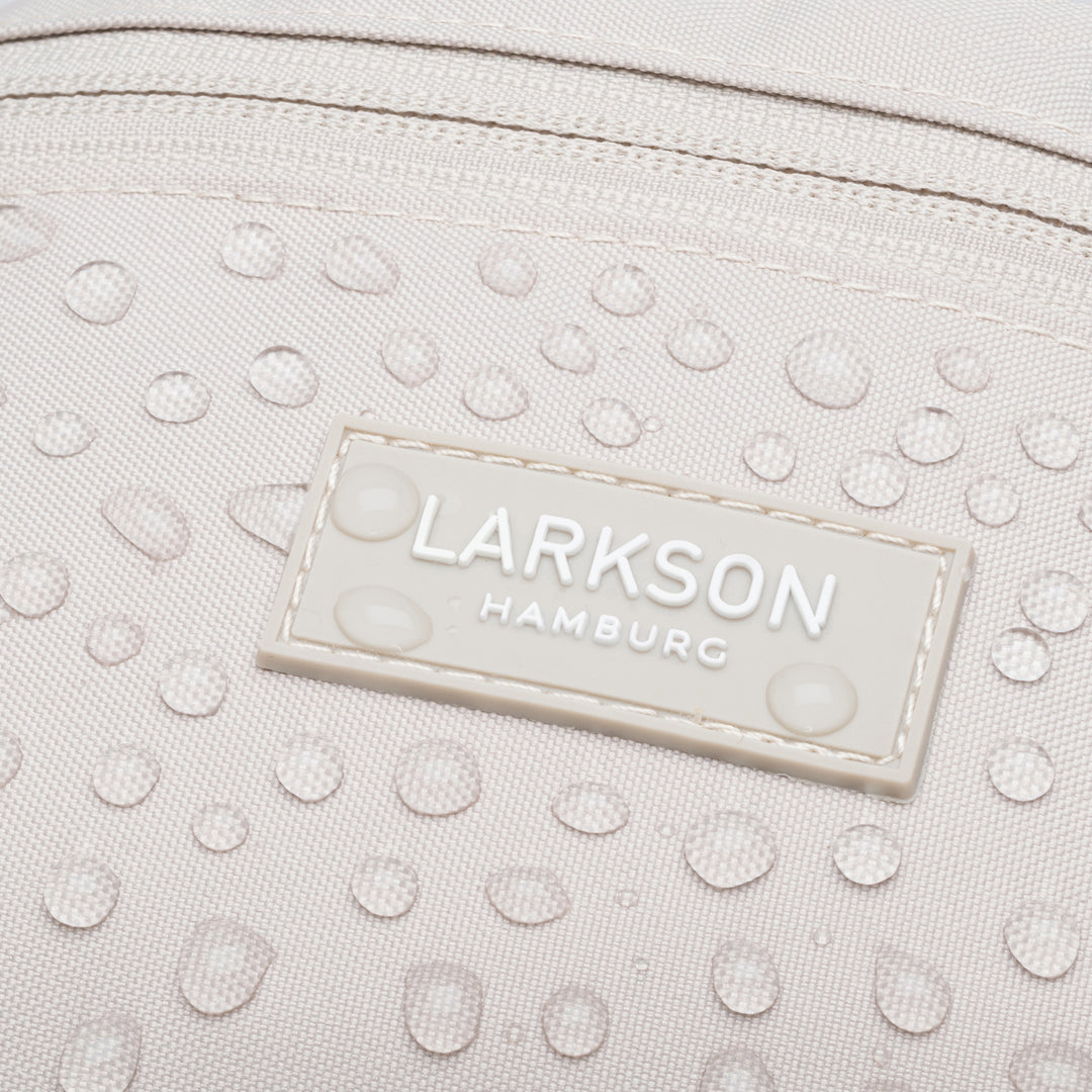 Nahaufnahme der wasserabweisenden beigen LARKSON Bauchtasche Finn mit sichtbaren Wassertropfen und Logo
