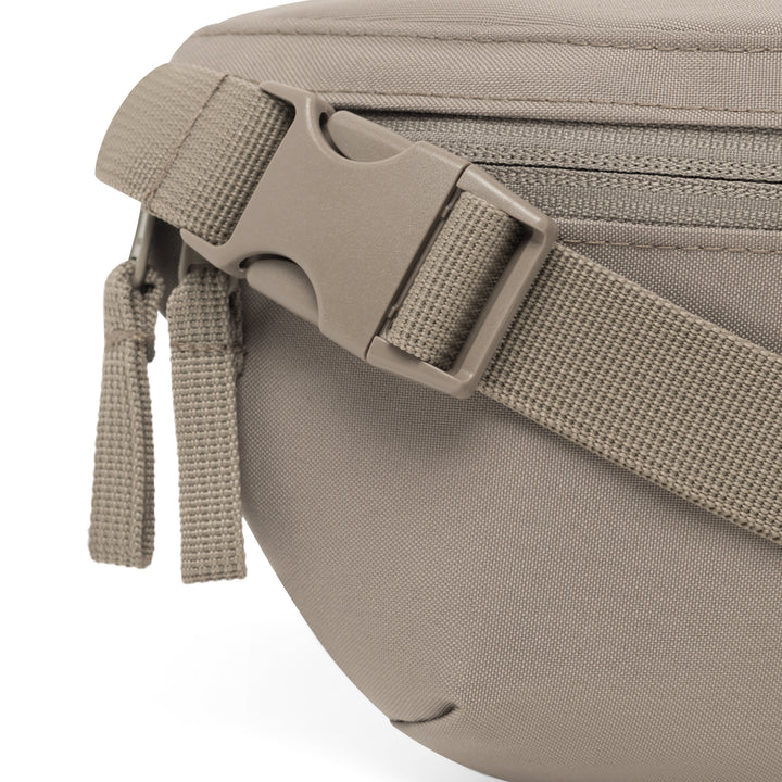 Nahaufnahme eines Verschlusses und Reißverschlussanhängers der Bauchtasche Finn in gravel Farbe