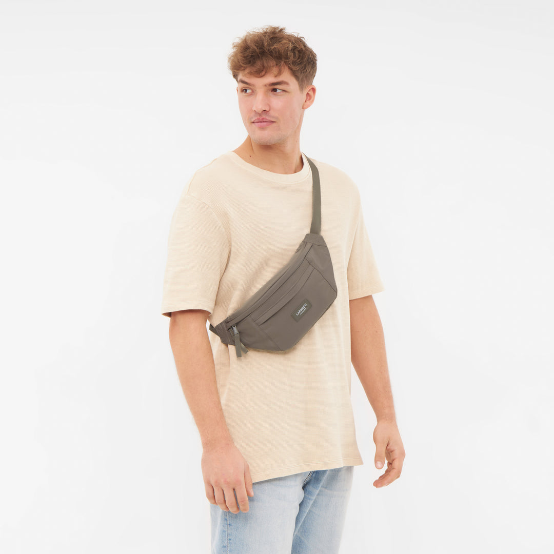 Mann trägt LARKSON Bauchtasche Ole in gravel Farbe diagonal über dem Oberkörper