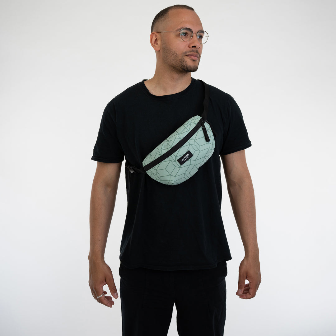 Mann trägt Bauchtasche Finn von LARKSON in hellgrün mit schwarzem geometrischem Muster quer über der Brust