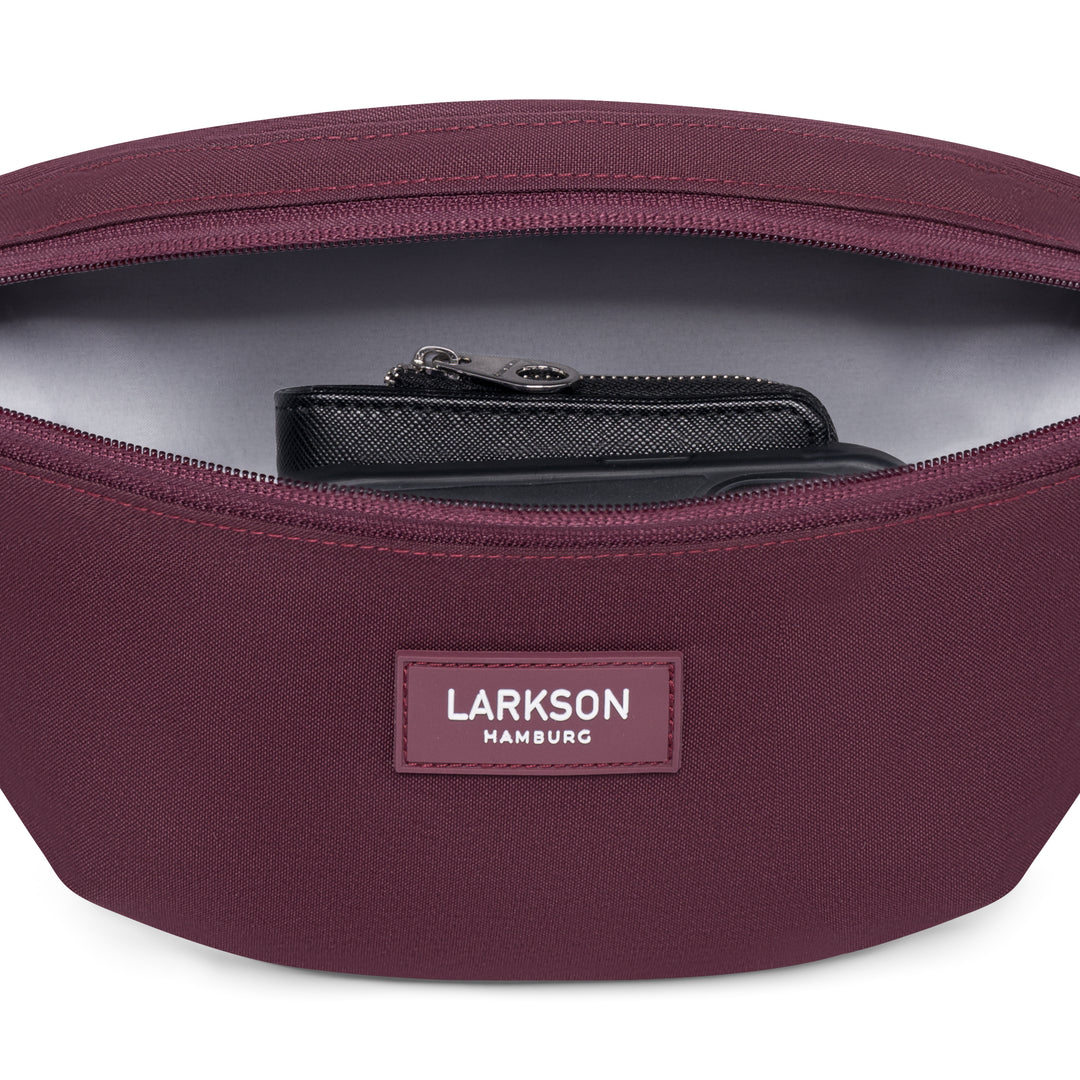 LARKSON Bauchtasche Finn in Beerenton mit geöffnetem Reißverschluss und sichtbarem schwarzen Portemonnaie innen