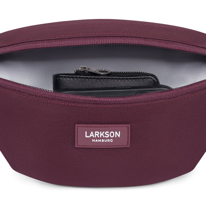 LARKSON Bauchtasche Finn in Beerenton mit geöffnetem Reißverschluss und sichtbarem schwarzen Portemonnaie innen