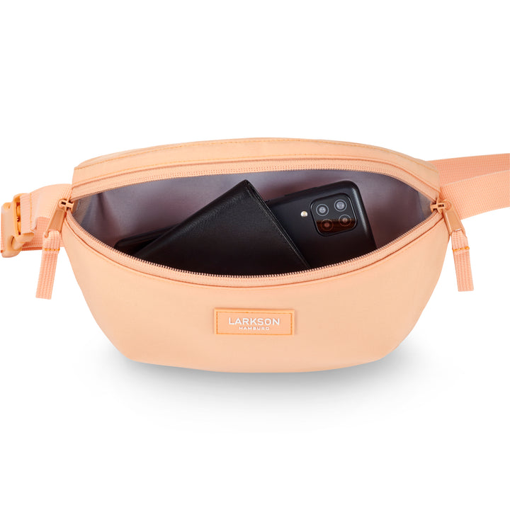 Larkson Bauchtasche Finn in Pfirsich mit geöffnetem Reißverschluss und darin sichtbarer schwarzer Geldbörse und Smartphone
