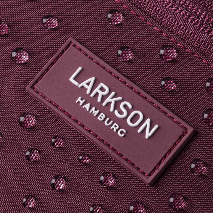 Nahaufnahme eines wasserdichten Beutels mit geprägtem Larkson Hamburg Logo in Beerenton