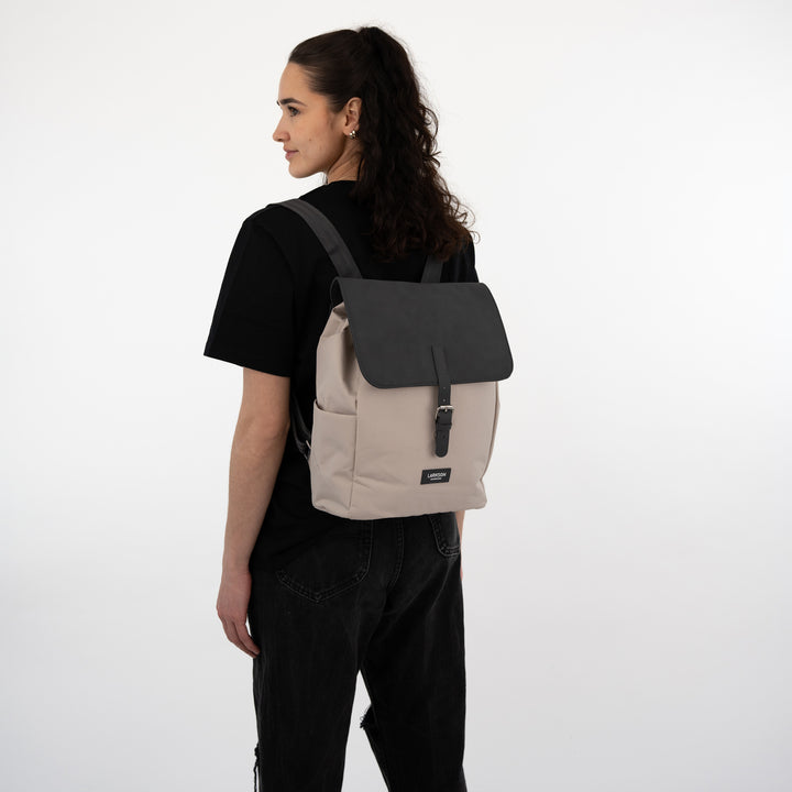Damen trägt den nachhaltigen LARKSON Rucksack Ida in beige mit schwarzer Klappe