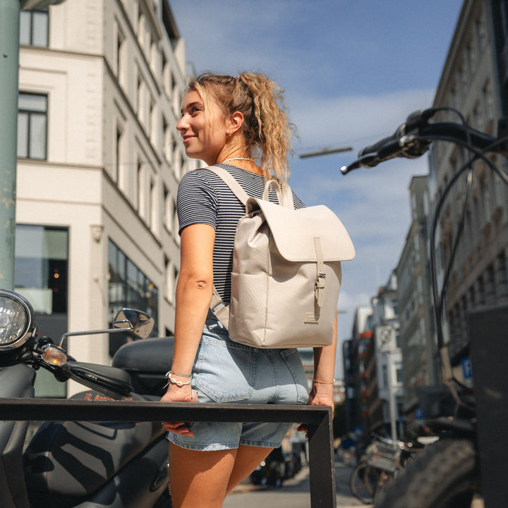 Junge Frau mit beigem Damenrucksack 'Ida' von LARKSON in moderner Stadtumgebung