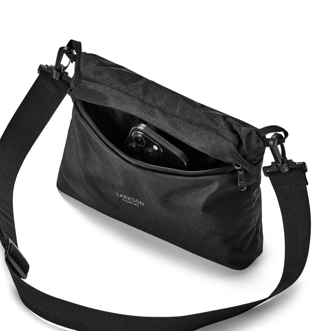 Schwarze LARKSON Umhängetasche mit Reißverschluss teilweise geöffnet, darin ein Smartphone