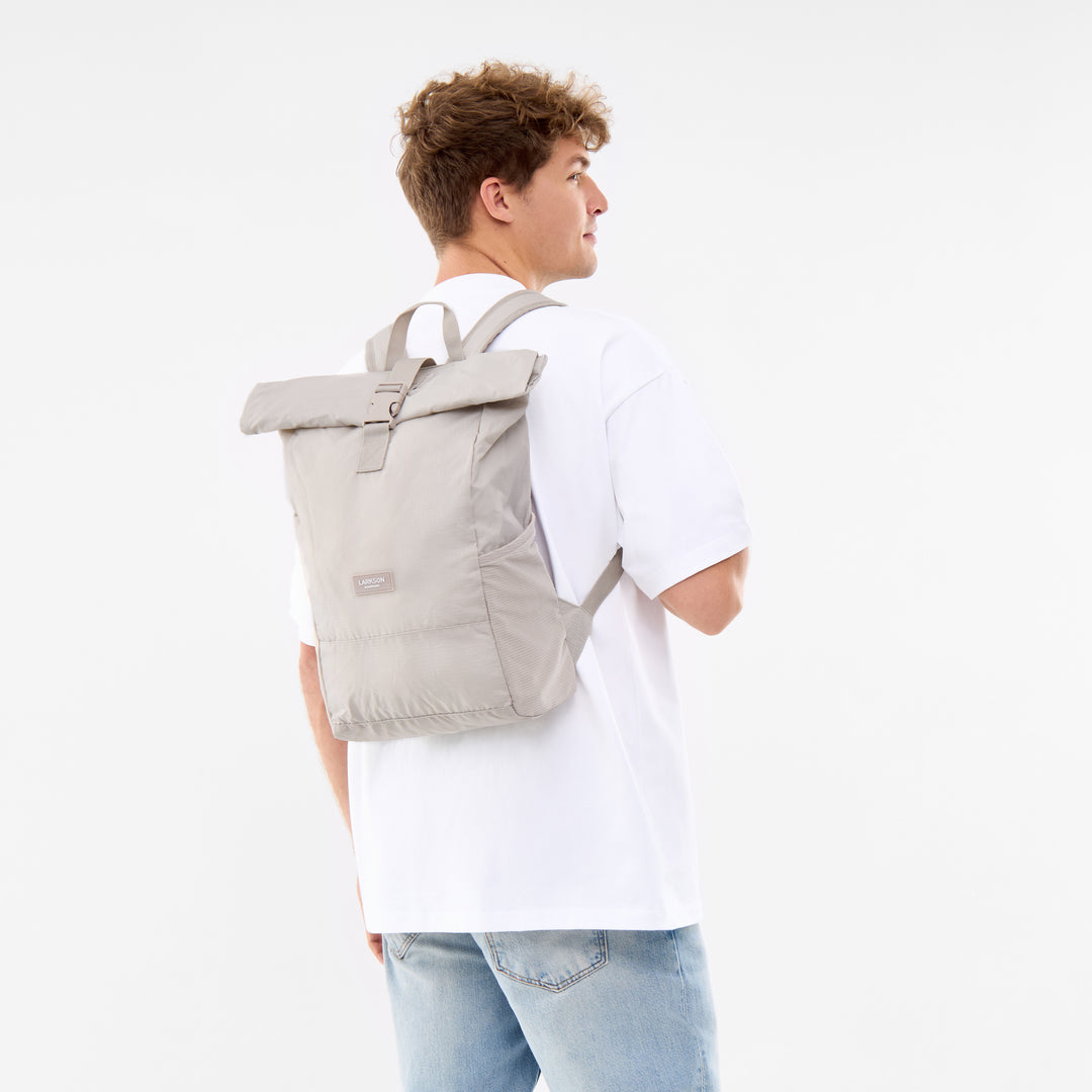 Mann trägt hellgrauen faltbaren Rolltop Rucksack Arne von LARKSON über weißem T-Shirt