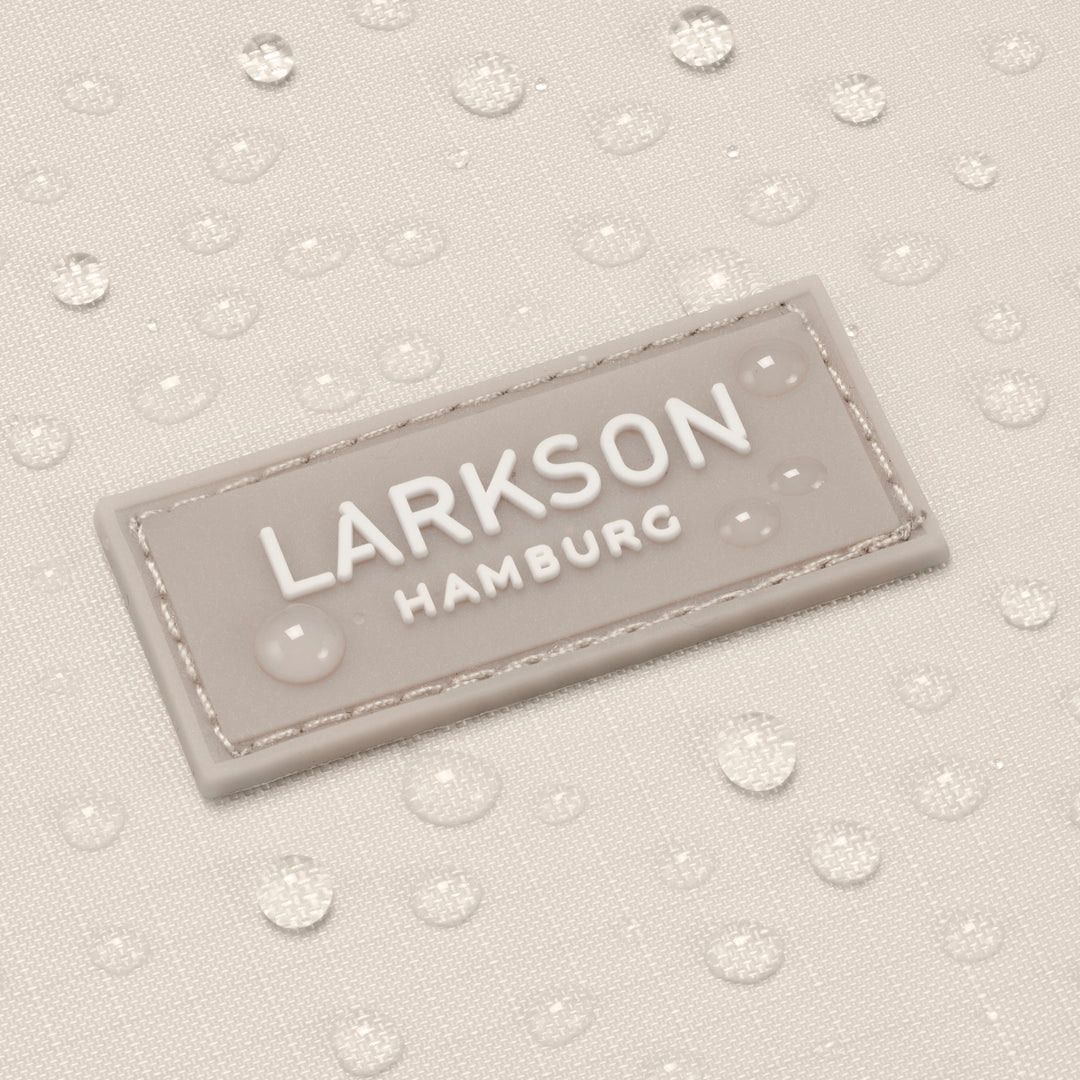 Wasserabweisender Stoff mit einem beigen eingenähten LARKSON Hamburg Logo auf dem faltbaren Rolltop Rucksack Arne