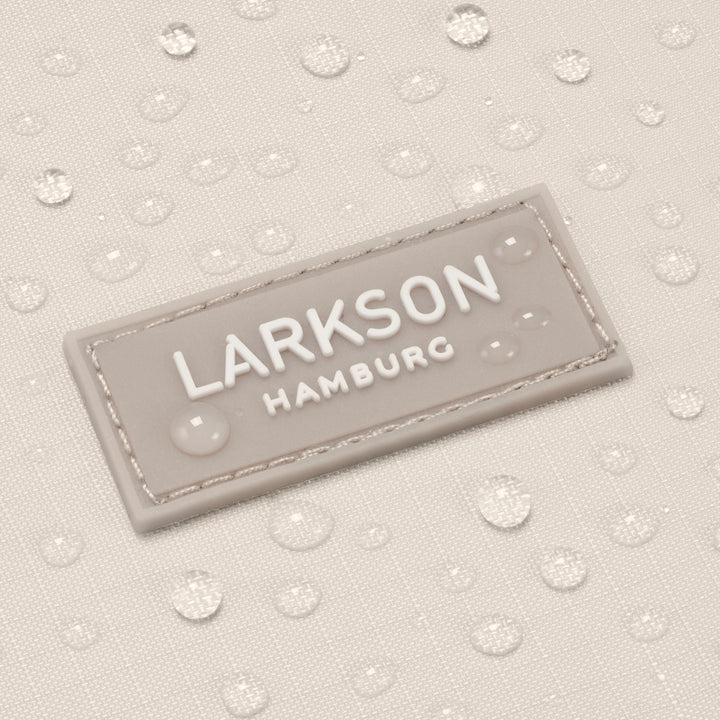 Wasserabweisender Stoff mit einem beigen eingenähten LARKSON Hamburg Logo auf dem faltbaren Rolltop Rucksack Arne