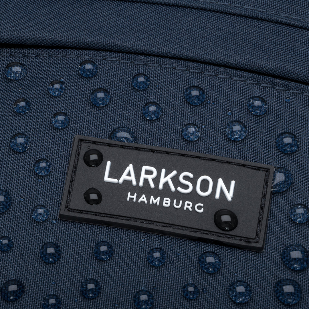 Nahaufnahme des wasserabweisenden blauen Larkson Bauchtasche Ole mit Logo auf dem Stoff und Wassertröpfchen