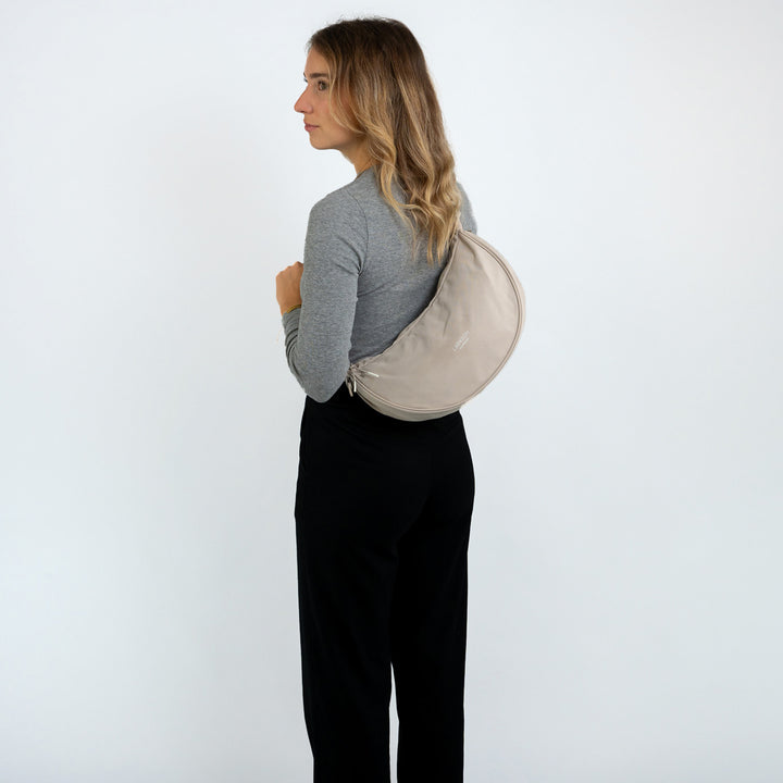 Frau mit halbmondförmiger beige LARKSON Half Moon Bag Solveig Medium Schultertasche