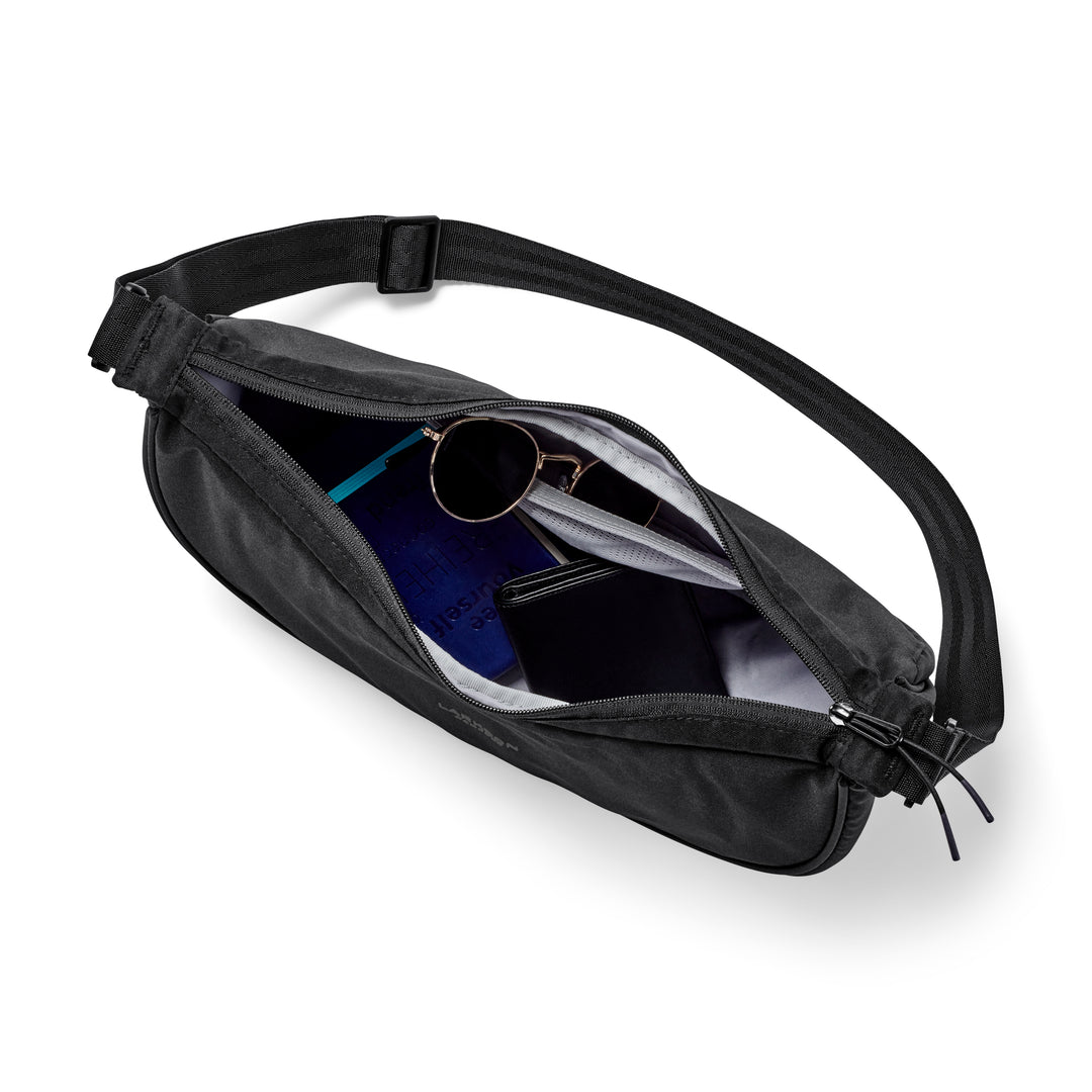 Schwarze Half Moon Bag Solveig Medium mit geöffnetem Reißverschluss, gezeigt werden Innenfächer mit Sonnenbrille, Geldbörse und Notizbuch
