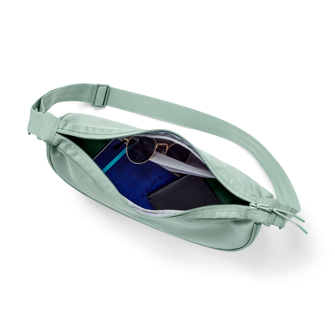 Mintfarbene Half Moon Bag Solveig Medium mit verstellbarem Gurt, geöffnet und Inhalt sichtbar