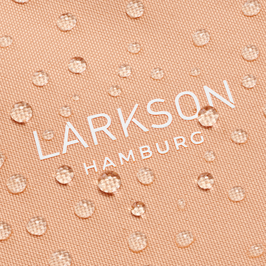 Detail der wasserabweisenden Oberfläche der peachfarbenen Half Moon Bag Solveig Medium mit weißem LARKSON Hamburg Schriftzug