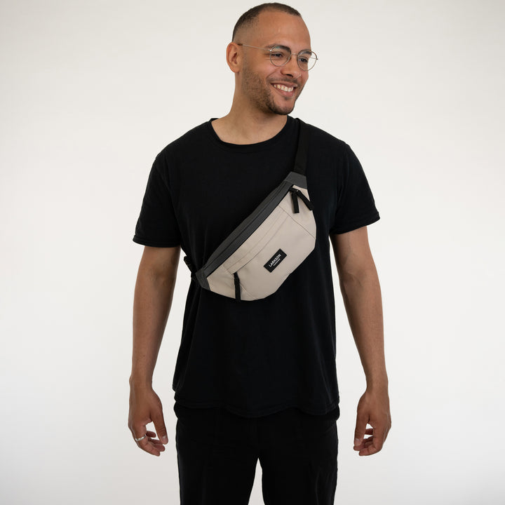 Mann trägt graue und beige Bauchtasche Ole von Larkson über der Brust zu schwarzem T-Shirt