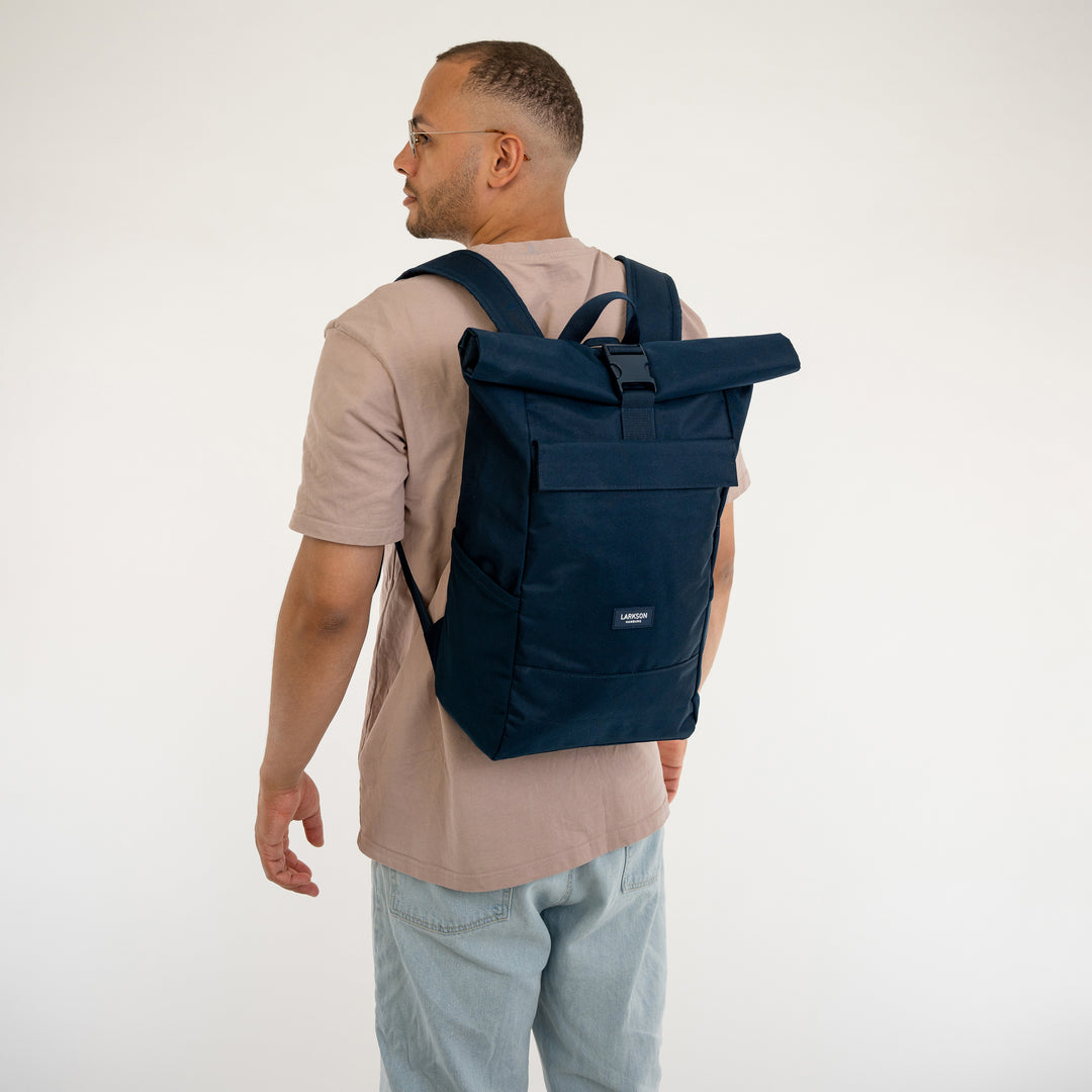 Mann mit braunem T-Shirt trägt blauen Rolltop Rucksack No 4 von LARKSON