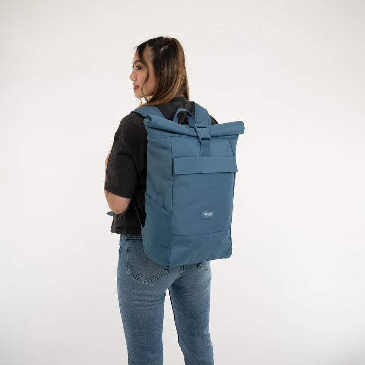 Frau trägt blauen LARKSON Rolltop Rucksack No 4, schlichte Form, aus robustem Material