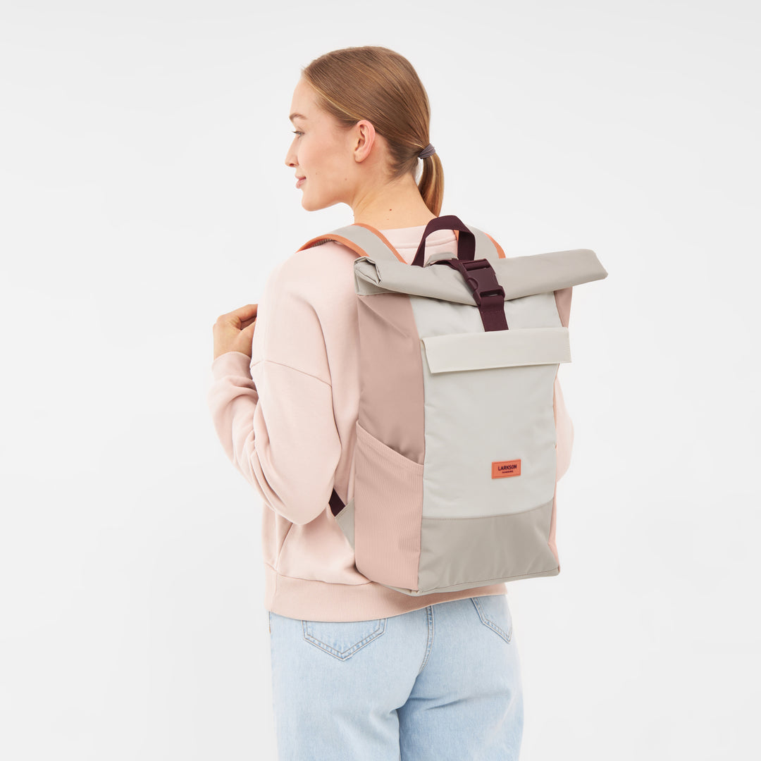 Frau trägt Rolltop Rucksack No 4 in Sand-Rose mit Fronttasche und schwarzem Verschluss