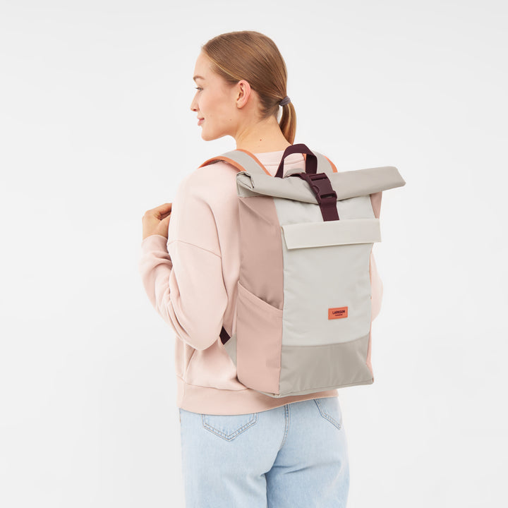 Frau trägt Rolltop Rucksack No 4 in Sand-Rose mit Fronttasche und schwarzem Verschluss