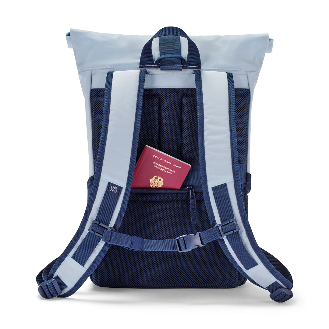 Rolltop Rucksack No 4 in Hellblau und Dunkelblau mit gepolstertem Rückenbereich und integriertem Reißverschlussfach, darin deutscher Reisepass
