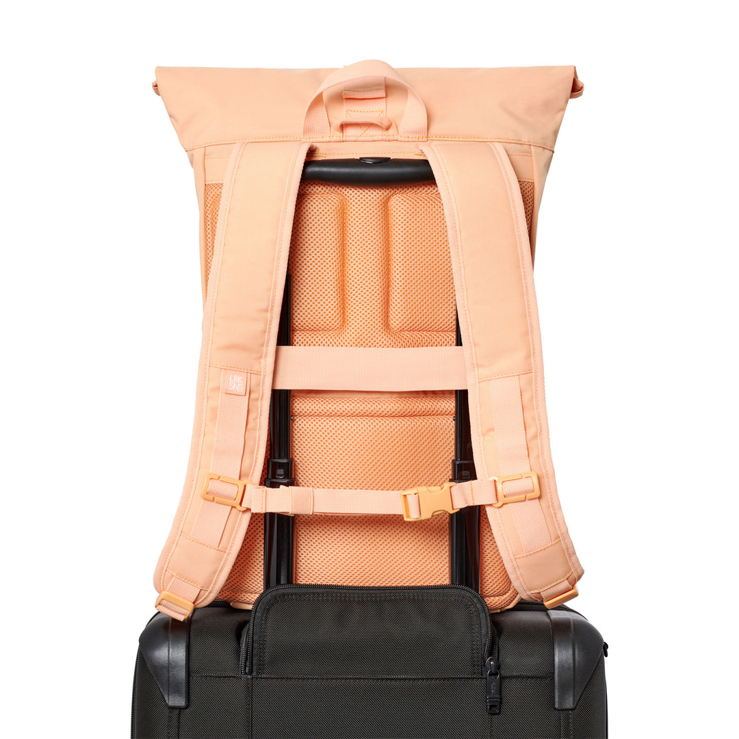 Rückenansicht des hellorangen Rolltop Rucksack No 4 von Larkson auf schwarzem Trolley-Griff befestigt