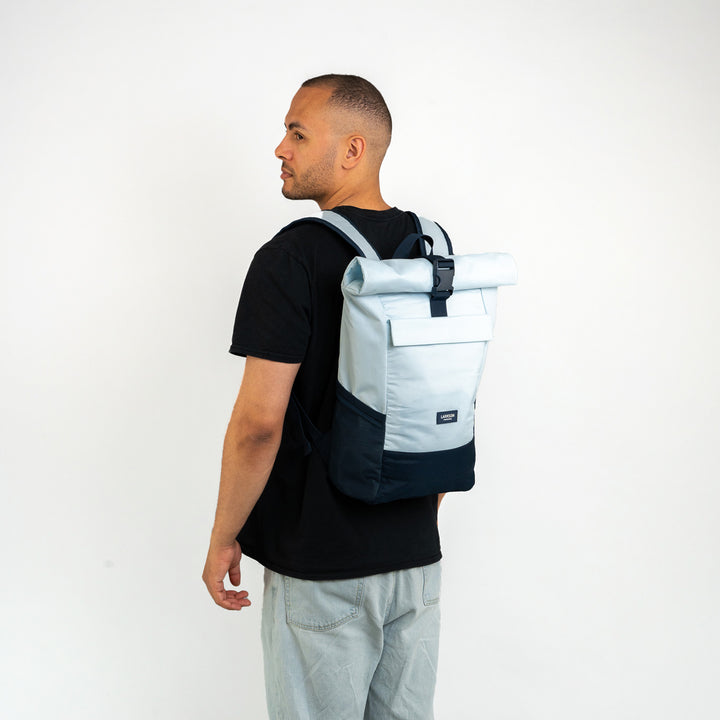 Mann mit Rolltop Rucksack No 4 in blau von LARKSON, trägt schwarzen T-Shirt und helle Jeans