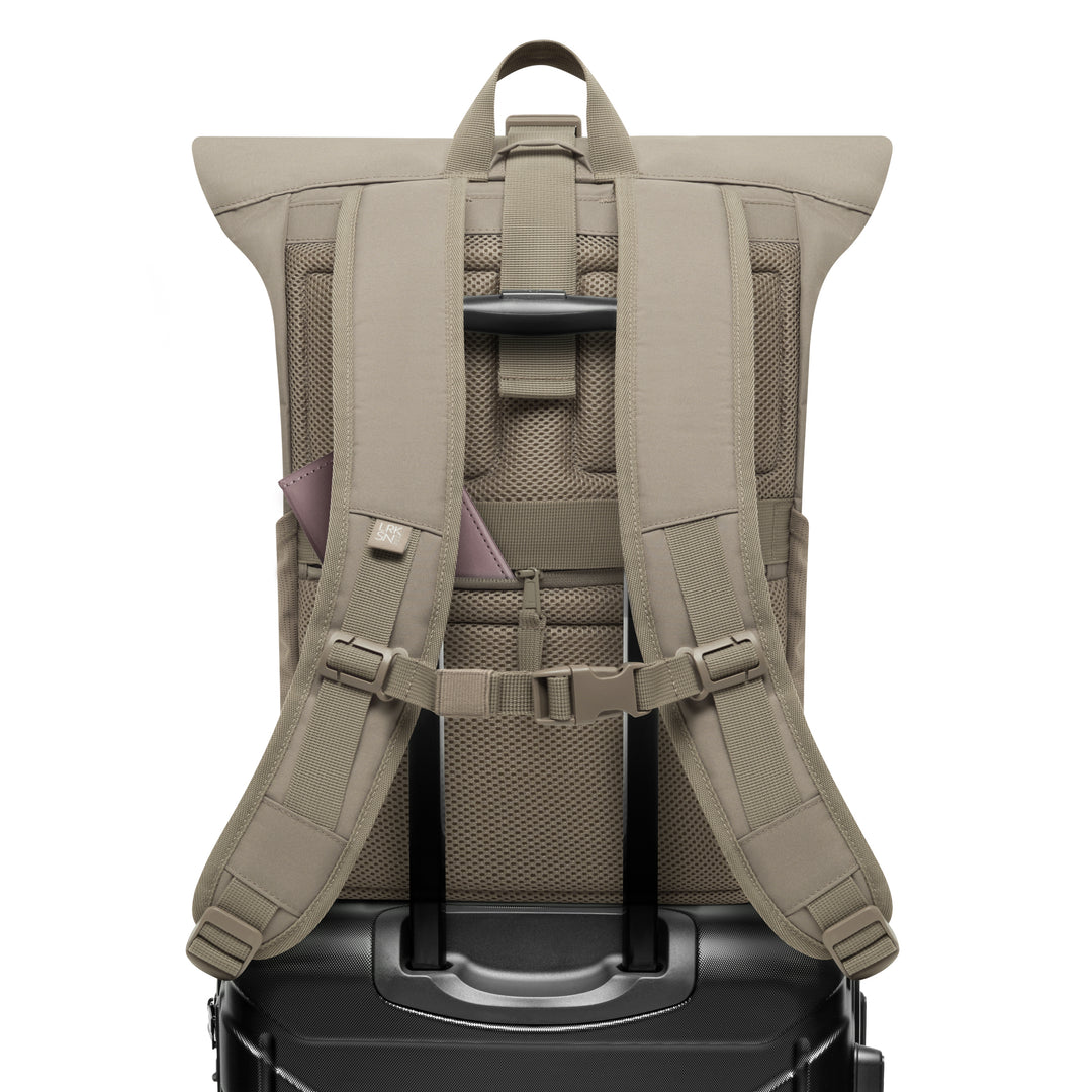 Beiger Rolltop Rucksack No 4 von LARKSON mit gepolsterten Schultergurten, Brustgurt und Befestigung an einem schwarzen Koffertrolley