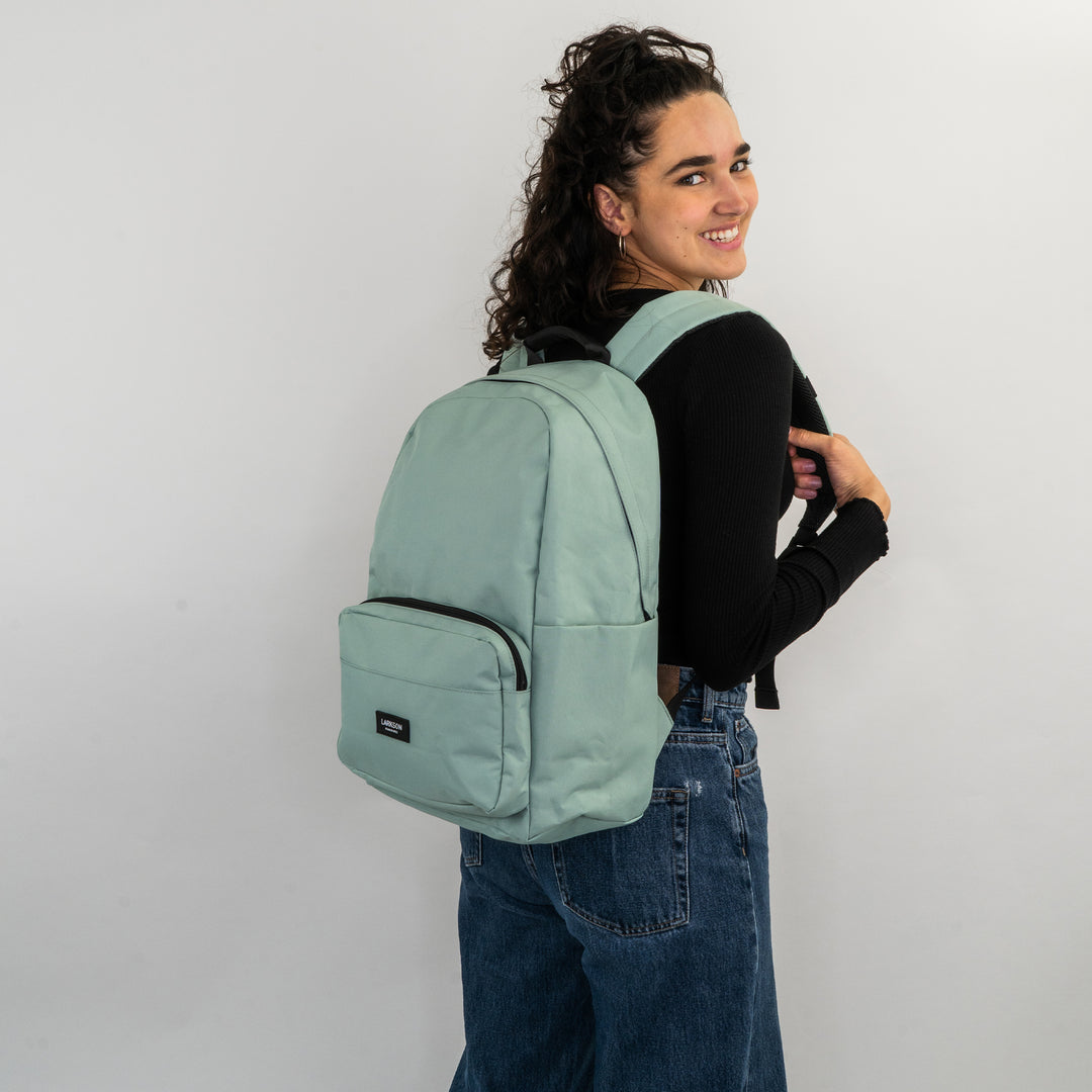 Frau mit mintgrünem Rucksack No 3 von LARKSON, trägt schwarzen Pullover und blaue Jeans