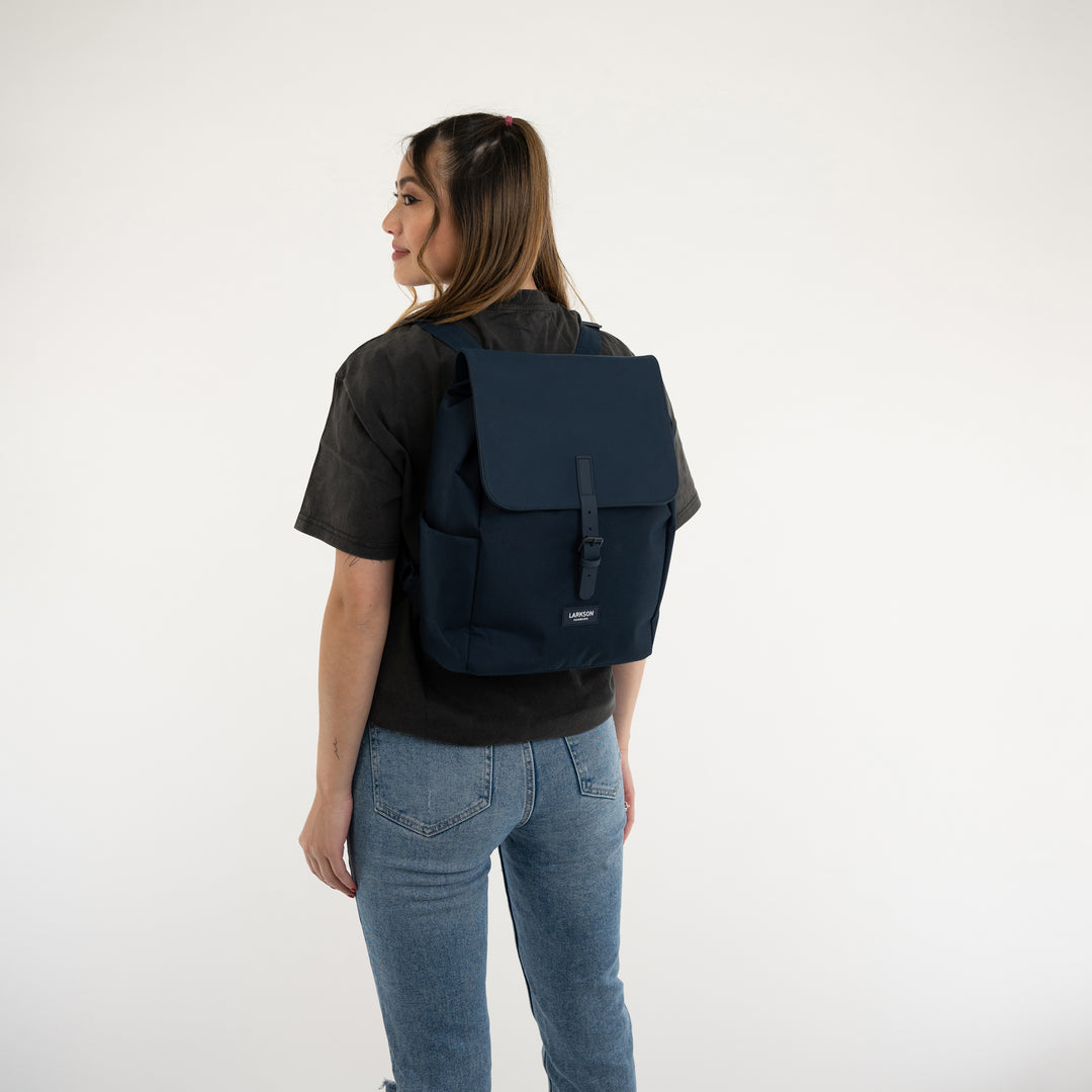 Frau trägt dunkelblauen Rucksack Ida von LARKSON mit klappbarem Verschluss und seitlichen Taschen