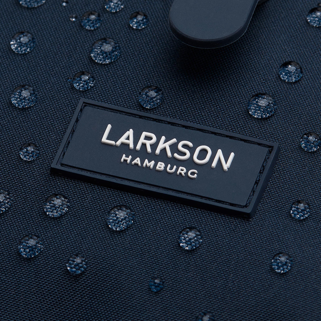 Nahaufnahme des wasserabweisenden blauen Rucksackes Ida mit LARKSON Hamburg Logo und Wasserperlen auf dem Stoff