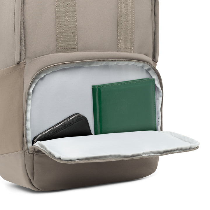 Beige Rucksack No 6 mit geöffneter Fronttasche, darin ein grünes Buch und eine schwarze Geldbörse