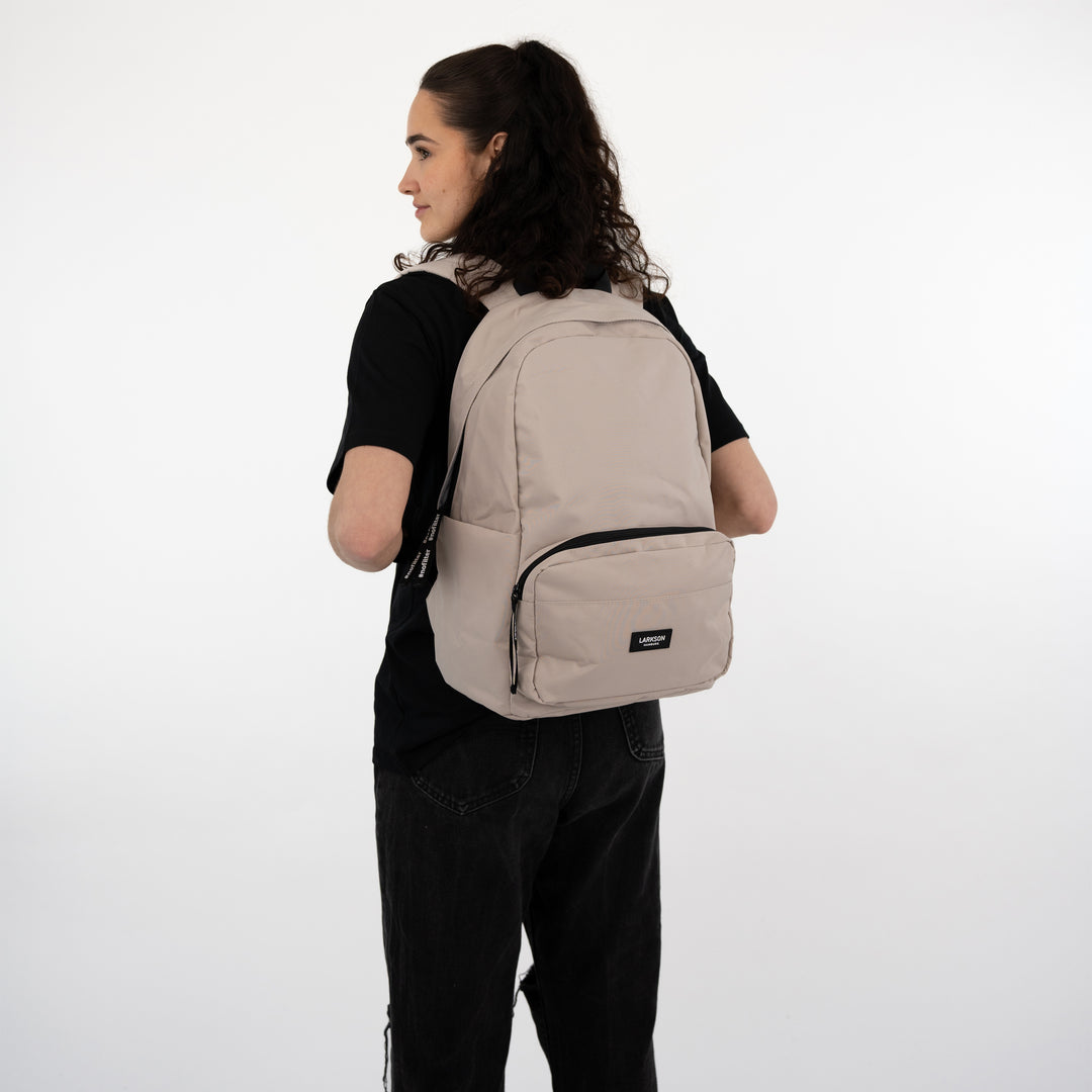 Beige LARKSON Rucksack No 3 getragen von jungen Frau in schwarzem T-Shirt und Hose