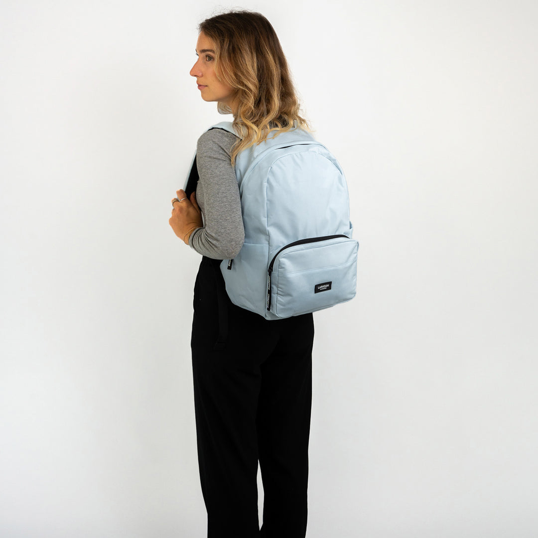 Jugendliche trägt hellblauen Rucksack No 3 von LARKSON, um Schulbedarf zu transportieren