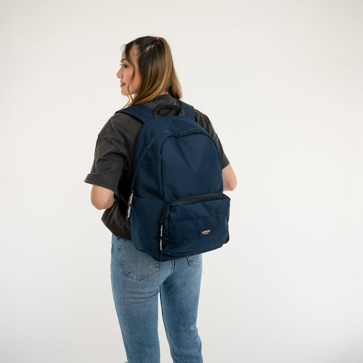 Blauer LARKSON Rucksack No 3 getragen von einem Mädchen in schwarzem T-Shirt und blauen Jeans