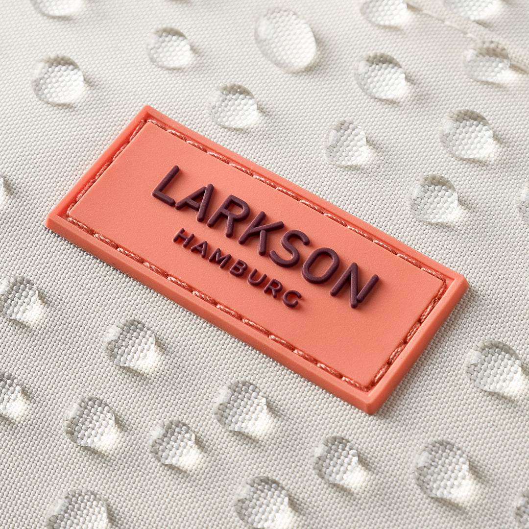 LARKSON Markenlogo auf beigem wasserdichtem Rucksackmaterial mit Wasserperlen