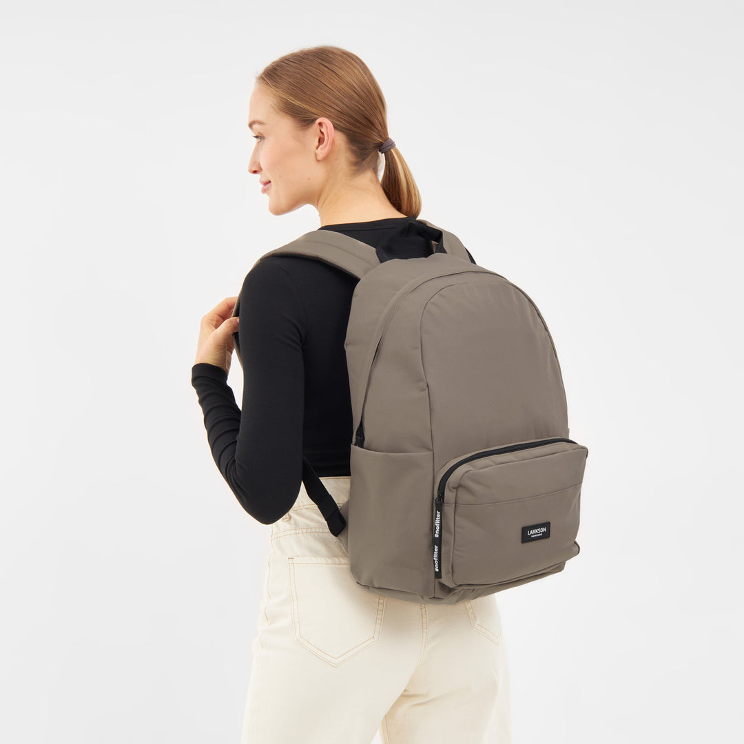Frau trägt LARKSON Rucksack No 3 in gravel mit Fronttasche und gepolsterten Schultergurten