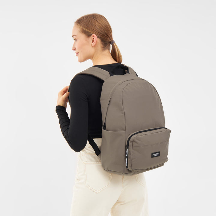 Frau trägt LARKSON Rucksack No 3 in gravel mit Fronttasche und gepolsterten Schultergurten